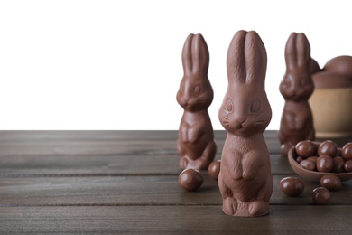 Photo of Chocolate Easter bunnies and candies on wooden table against white background. Space for text