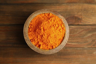 Photo of Aromatic saffron powder in bowl on wooden table, top view