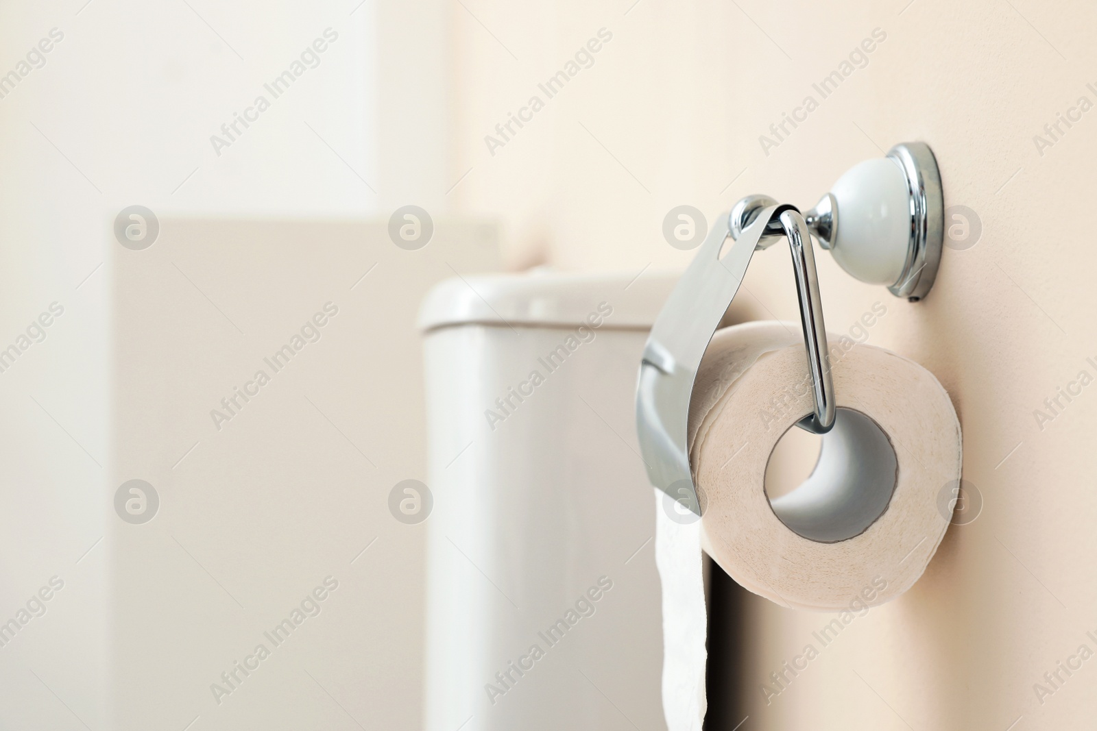 Photo of Holder with toilet paper roll on wall in bathroom. Space for text