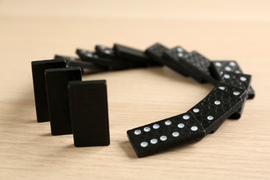 Photo of Black domino tiles falling on wooden table