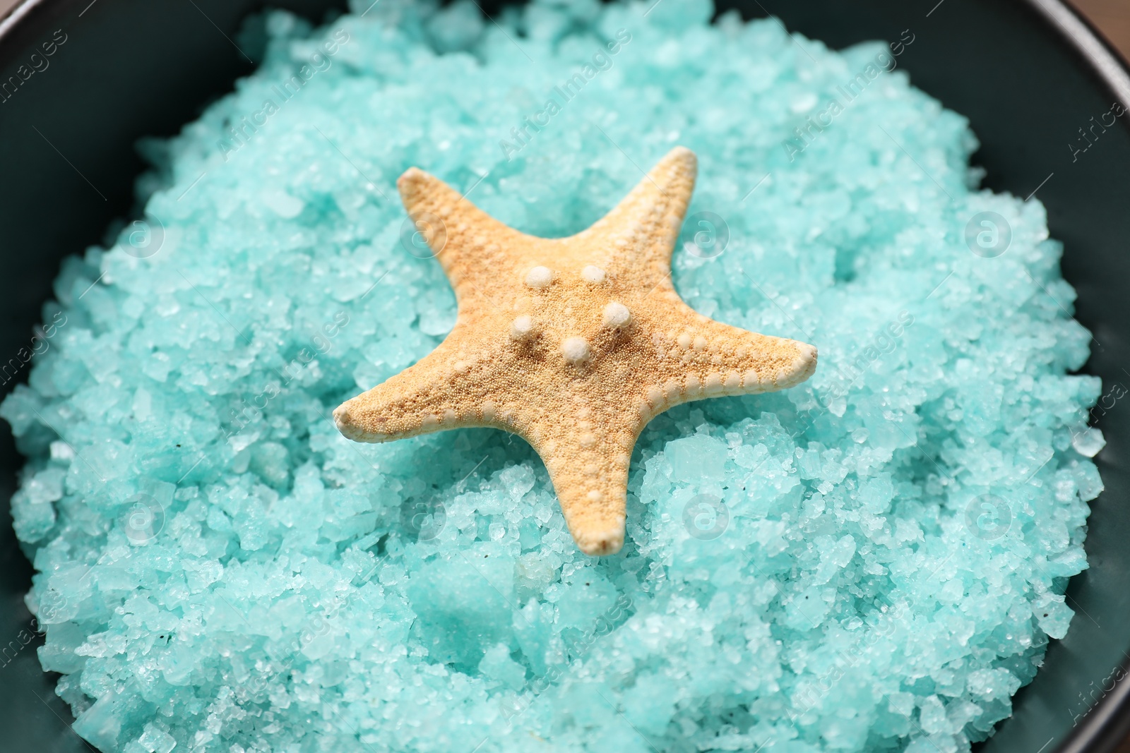 Photo of Light blue sea salt and starfish in bowl, closeup