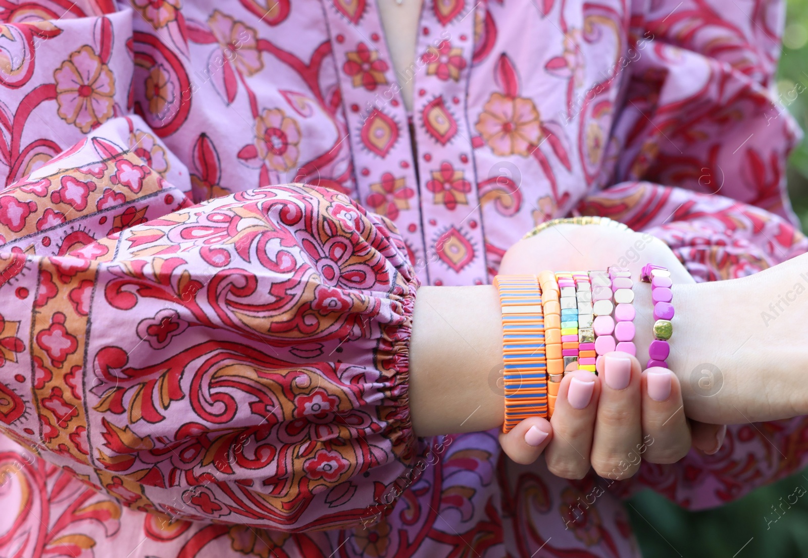 Photo of Woman wearing many stylish bracelets outdoors, closeup