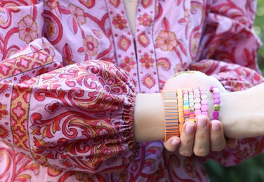 Photo of Woman wearing many stylish bracelets outdoors, closeup