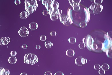 Photo of Beautiful transparent soap bubbles on purple background