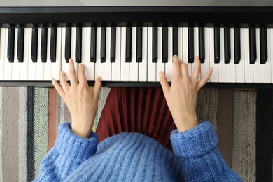 Photo of Young woman playing piano at home, top view