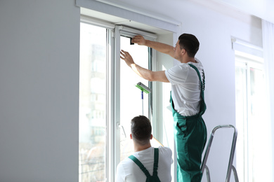 Photo of Professional workers tinting window with foil indoors