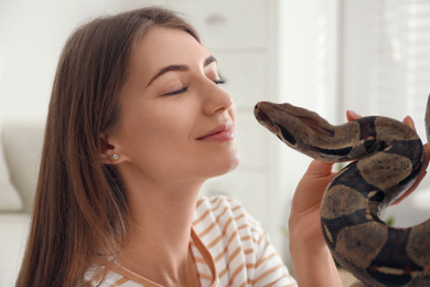 Young woman with boa constrictor at home. Exotic pet