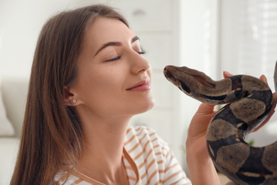 Photo of Young woman with boa constrictor at home. Exotic pet