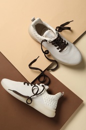 Stylish sneakers with brown shoe laces on color background, flat lay
