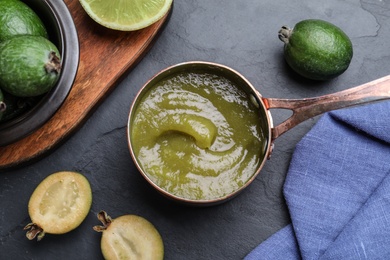 Feijoa jam and fresh fruits on black table, flat lay