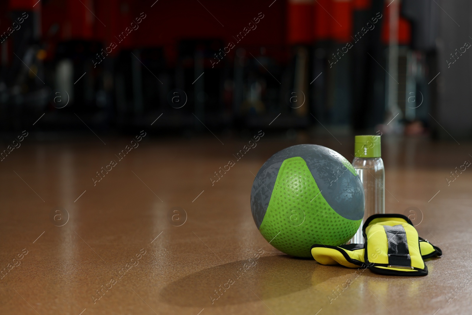 Photo of Medicine ball, bottle and weighting agents on floor in gym. Space for text