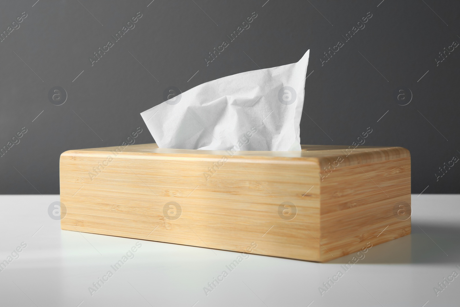 Photo of Wooden holder with paper tissues on white table