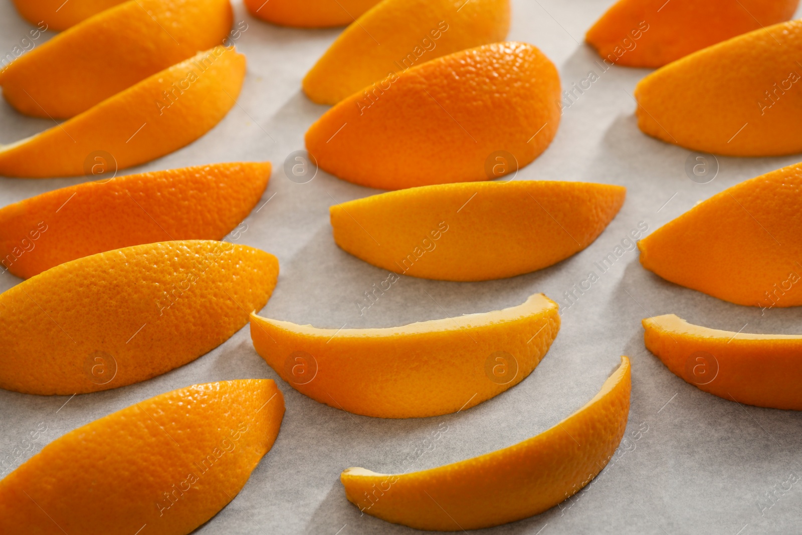 Photo of Fresh orange peels on white parchment paper, closeup