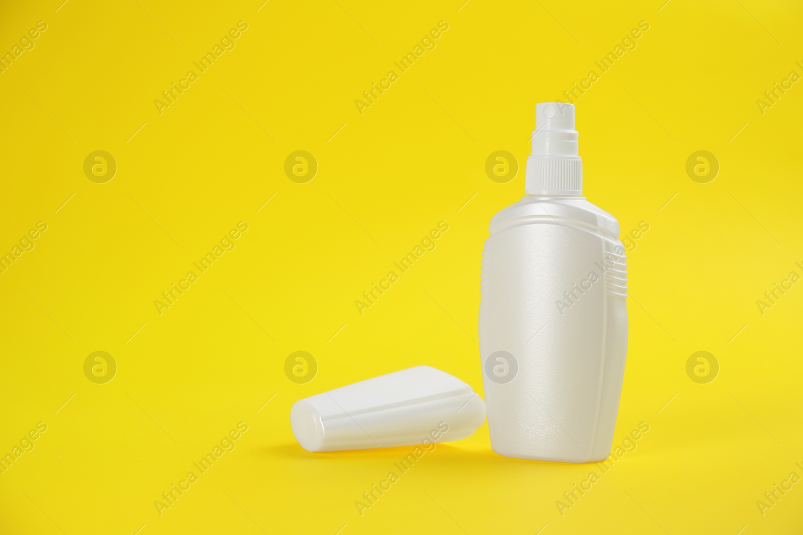 Photo of Bottle with insect repellent spray on yellow background