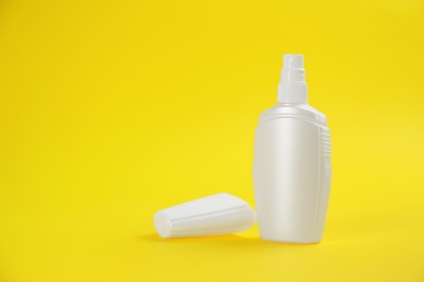 Photo of Bottle with insect repellent spray on yellow background