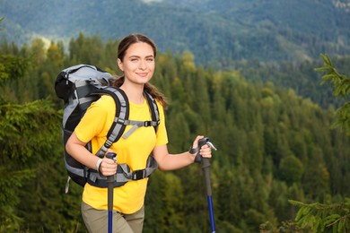 Woman with backpack and trekking poles hiking in mountains. Space for text