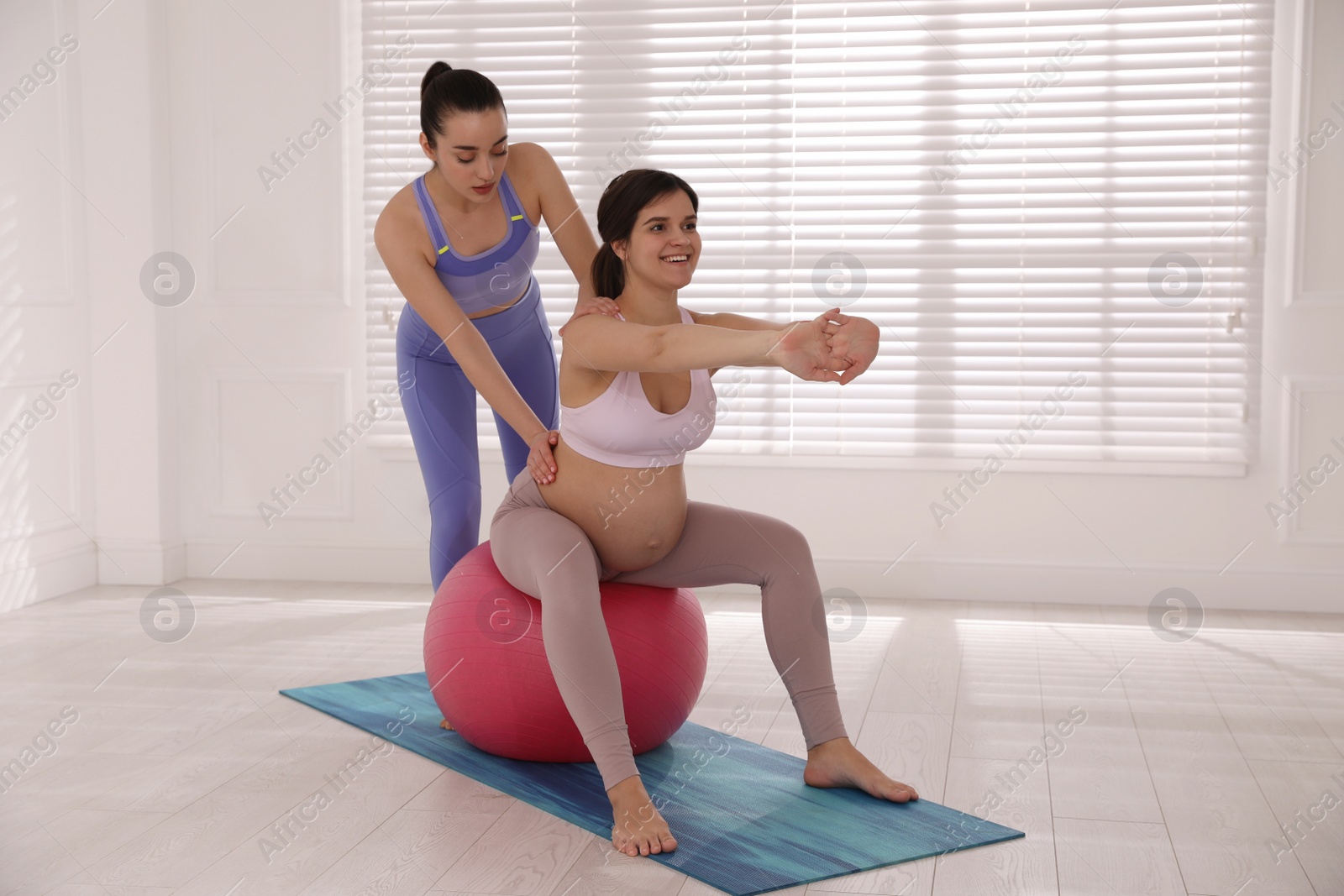 Photo of Trainer working with pregnant woman in gym. Preparation for child birth