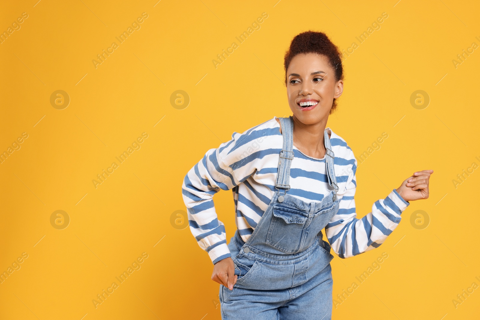 Photo of Happy young woman dancing on orange background. Space for text