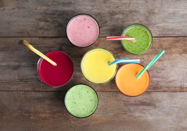 Glasses with delicious detox smoothies on wooden background, top view