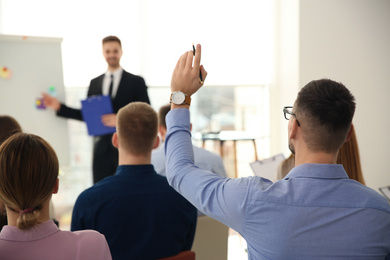 Photo of Man raising hand to ask question at business training indoors