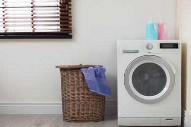 Photo of Modern washing machine and laundry basket indoors