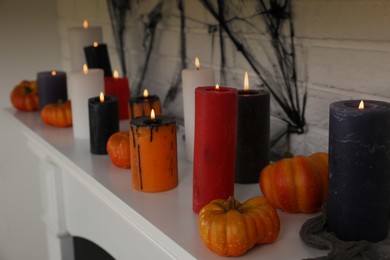 Candles and pumpkins on fireplace indoors, closeup. Halloween decor