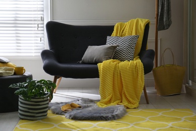 Comfortable sofa with pillows and plaid in living room. Interior design