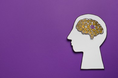 Top view of human head cutout with brain on purple background, space for text. Epilepsy awareness