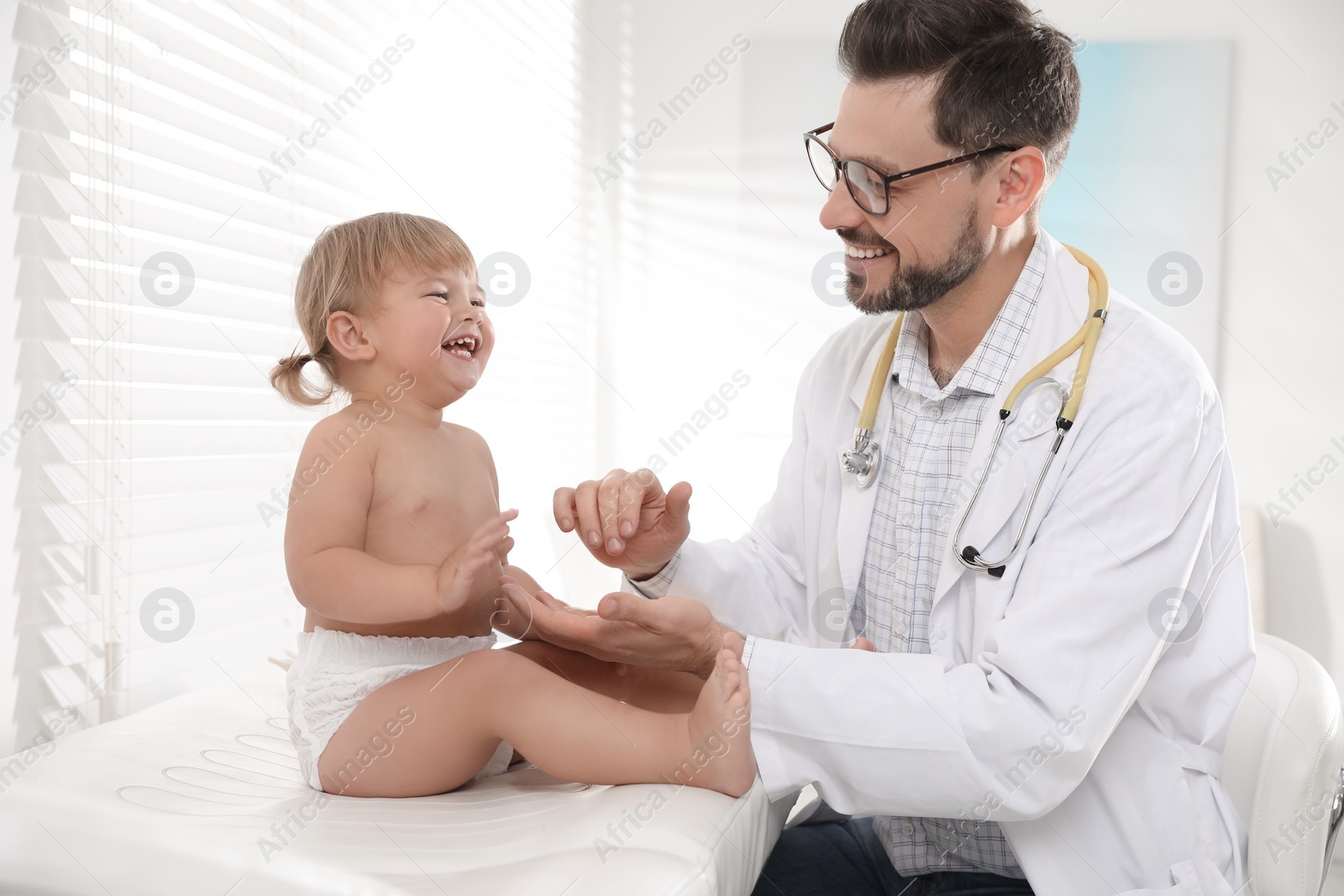 Photo of Pediatrician examining cute little baby in clinic