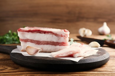 Photo of Tasty salt pork with garlic on wooden table