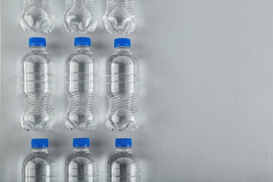 Photo of Bottles of water on light background, top view. Space for text