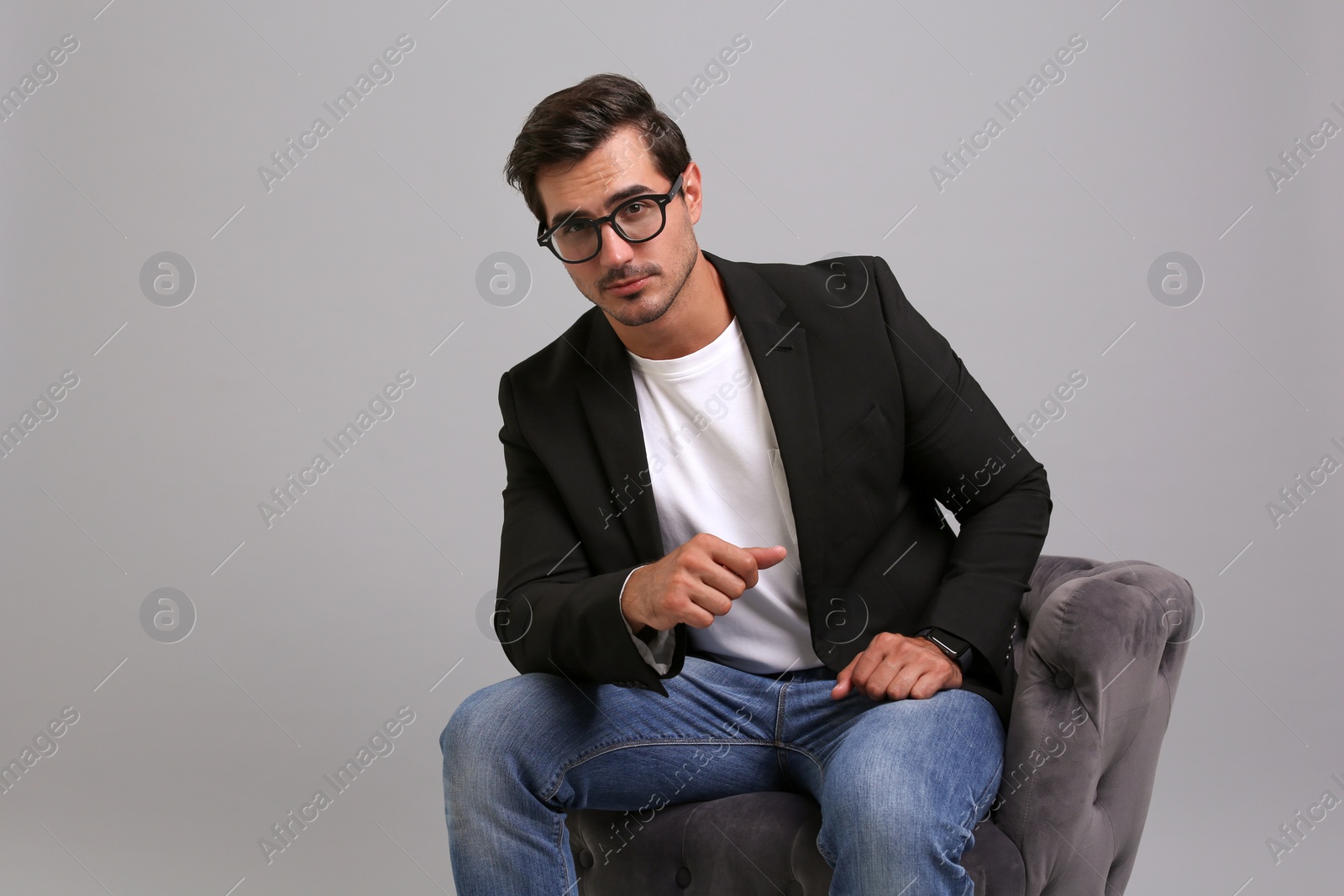 Photo of Handsome young businessman sitting in armchair on grey background