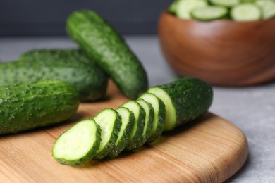 Photo of Whole and cut fresh ripe cucumbers on wooden board, closeup