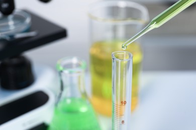 Photo of Laboratory analysis. Dripping liquid into test tube on table, closeup