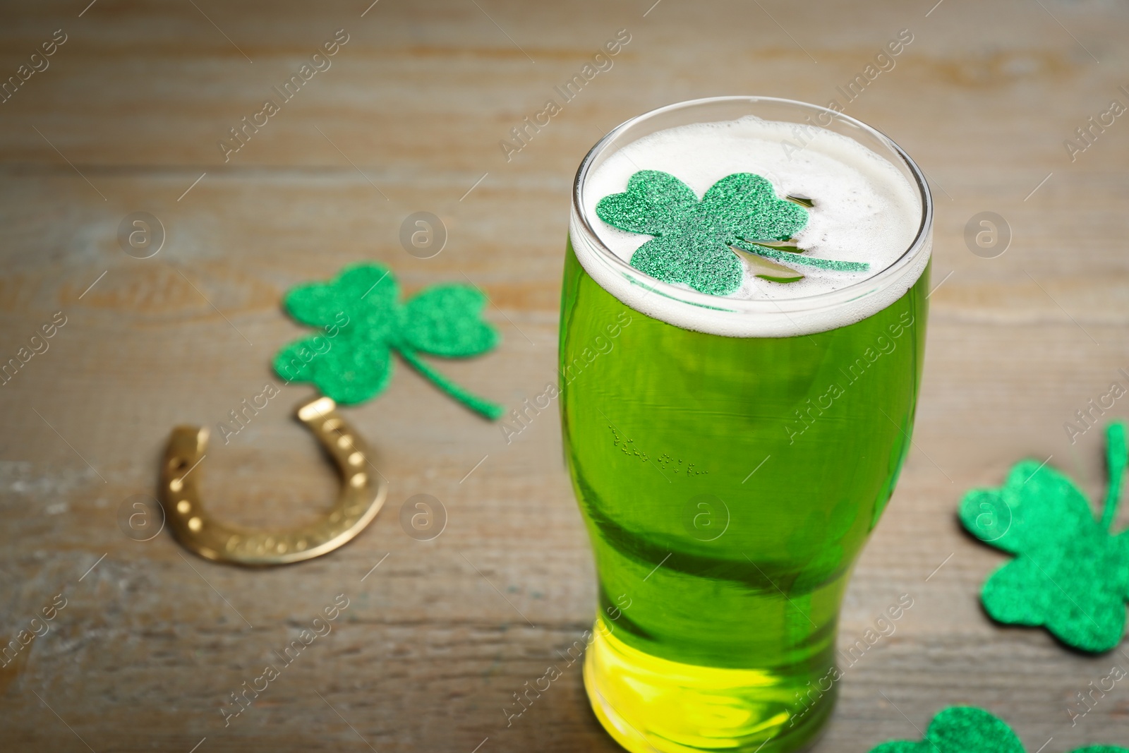 Photo of Green beer and clover on wooden table, space for text. St. Patrick's Day celebration