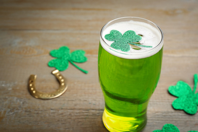 Photo of Green beer and clover on wooden table, space for text. St. Patrick's Day celebration