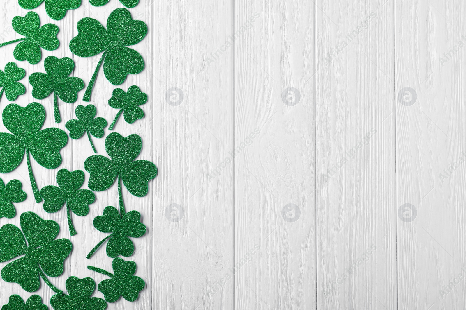 Photo of Flat lay composition with clover leaves on white wooden table, space for text. St. Patrick's Day celebration