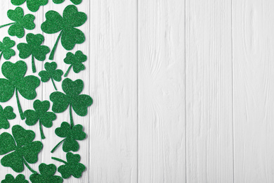 Flat lay composition with clover leaves on white wooden table, space for text. St. Patrick's Day celebration