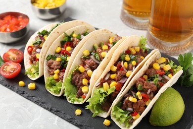 Photo of Delicious tacos with meat and vegetables on light gray marble table, closeup