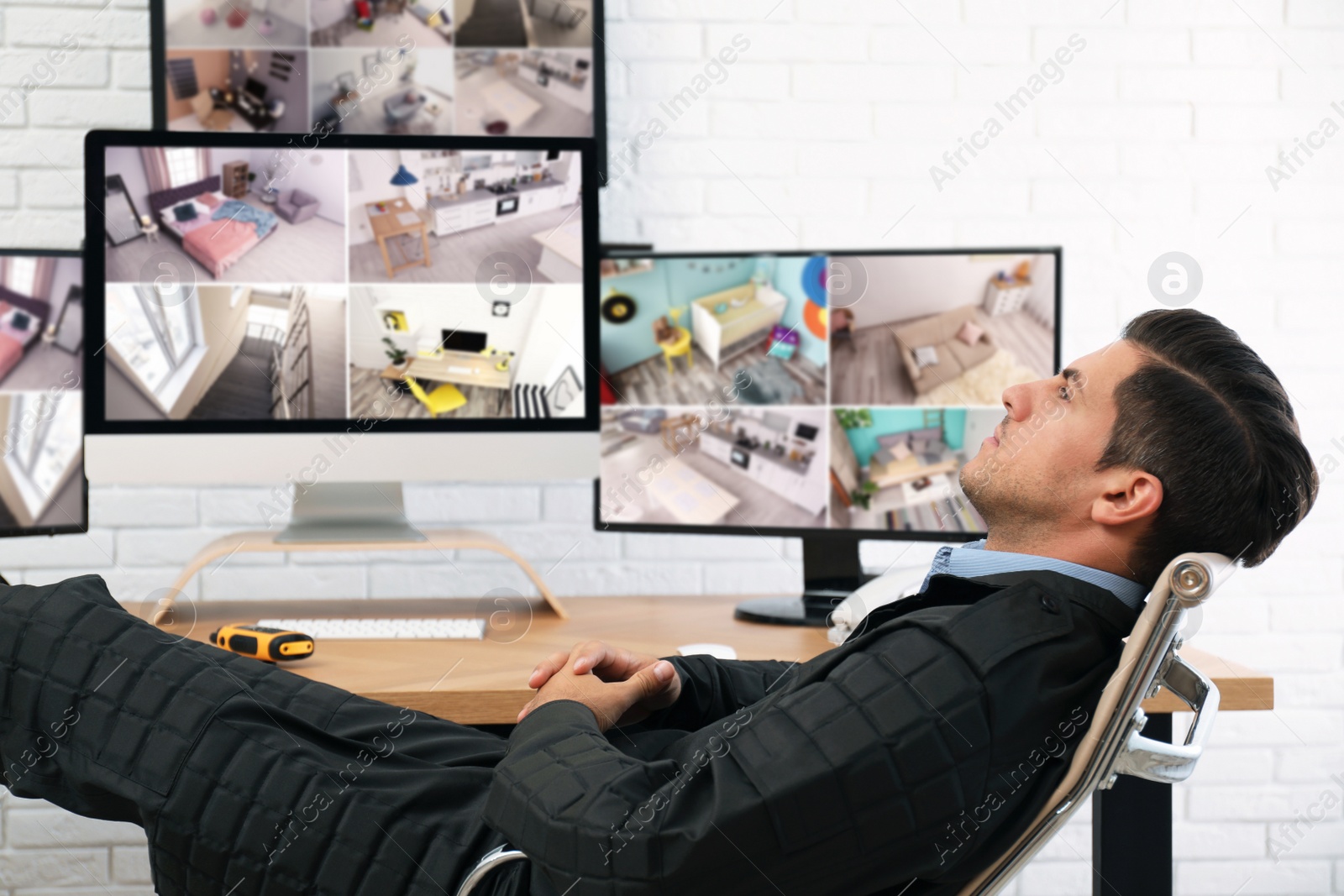 Photo of Male security guard resting near monitors at workplace