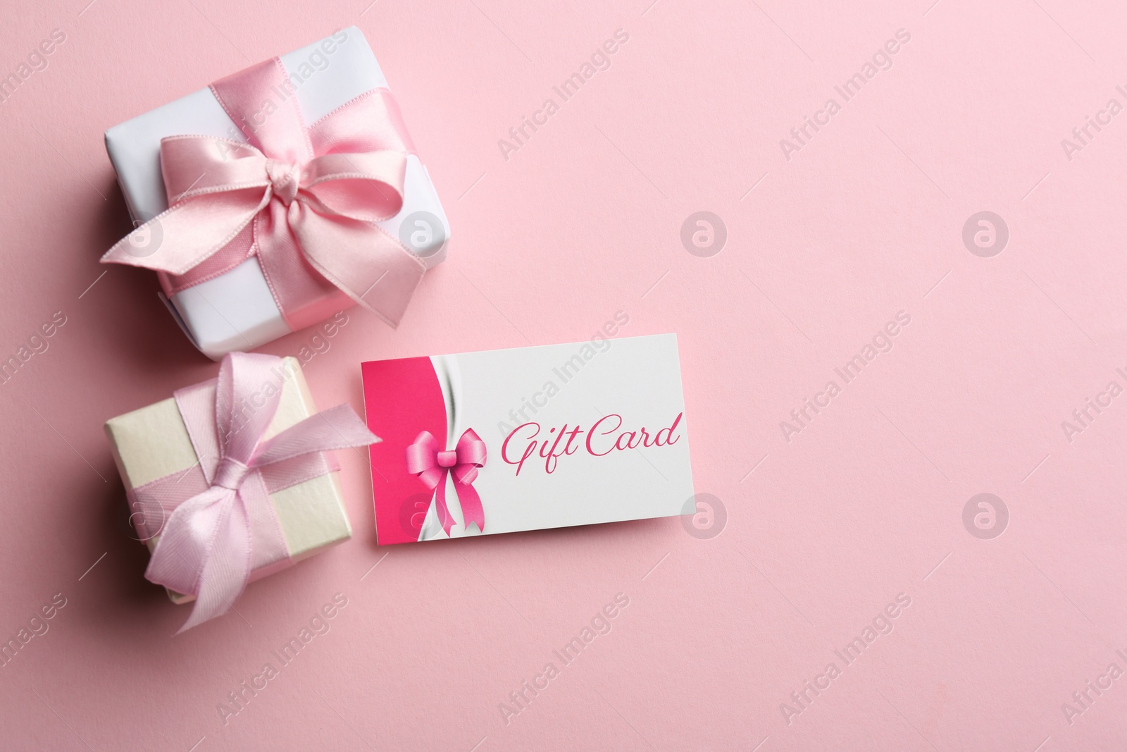 Photo of Gift card and presents on pink background, flat lay. Space for text