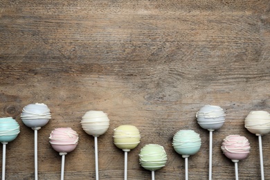 Photo of Sweet cake pops on wooden background, flat lay. Space for text