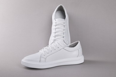 Photo of Pair of stylish white sneakers on grey background