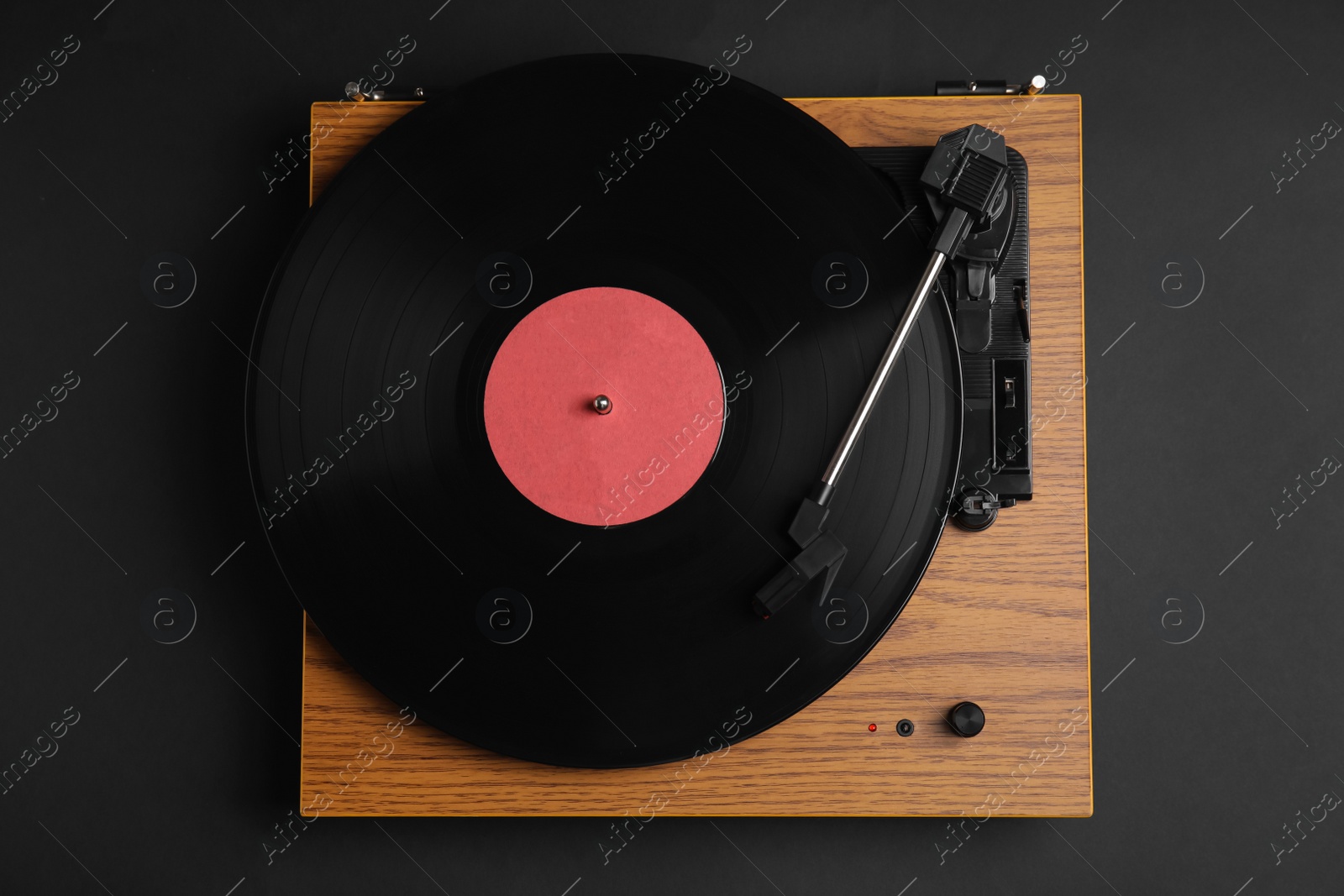 Photo of Modern vinyl record player with disc on black background, top view