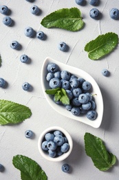 Flat lay composition with juicy blueberries and green leaves on color table