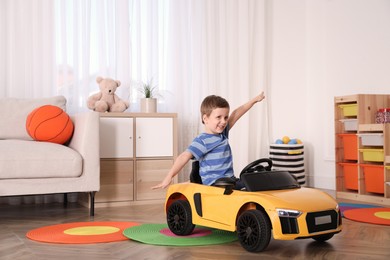 Photo of Little child playing with toy car in room