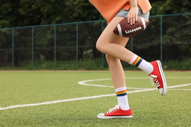 Photo of Woman with football ball wearing red classic old school sneakers on green court outdoors, closeup. Space for text