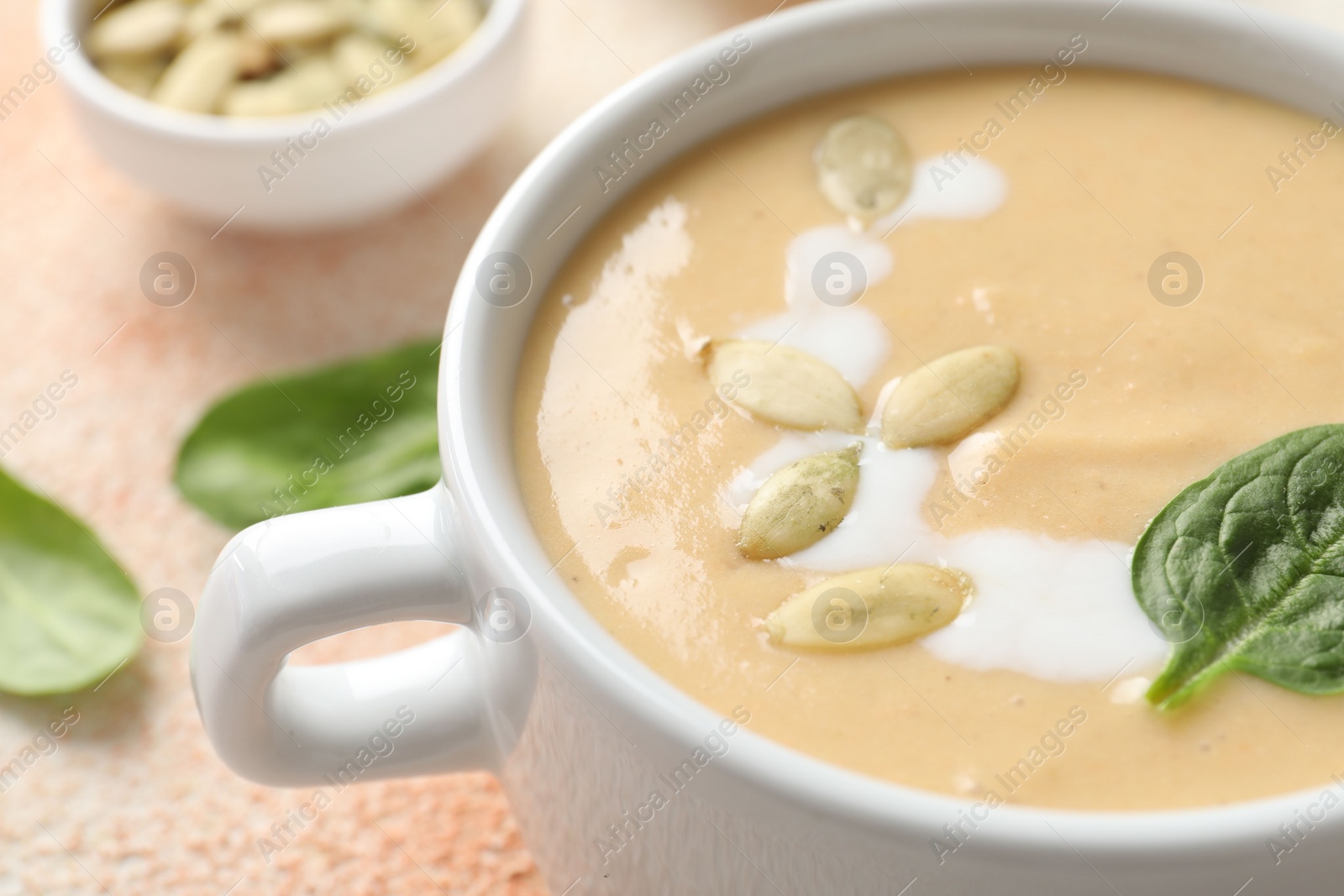 Photo of Healthy cream soup high in vegetable fats on color textured table, closeup