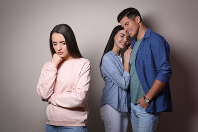 Photo of Unhappy woman feeling jealous while couple spending time together on grey background