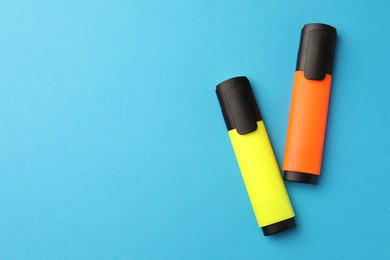 Photo of Bright markers on light blue background, flat lay. Space for text
